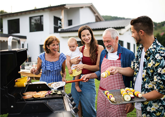 Family enjoying a backyard barbecue with grandparents, parents, and baby sharing moments and discussing baby name regrets.
