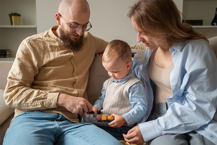 Parents playing with baby boy at home, illustrating baby names parents regret giving their kids in family setting.