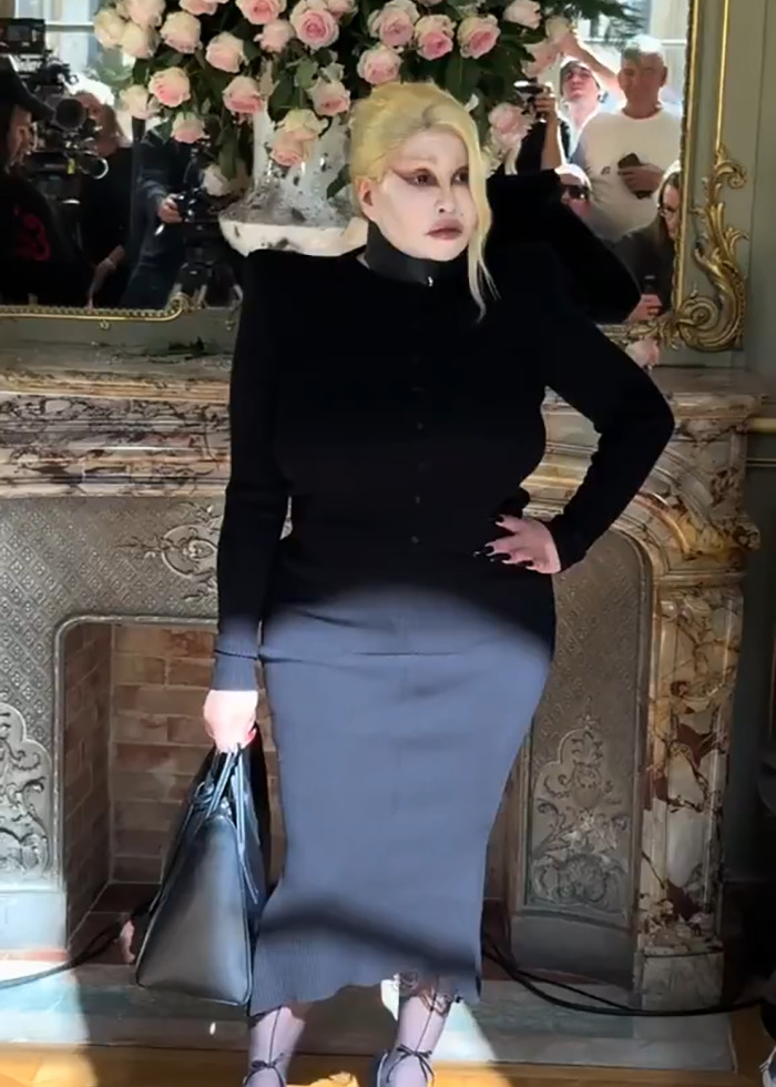 Model in bold black outfit and dramatic makeup posing during a Paris Fashion Week show stirring controversy.