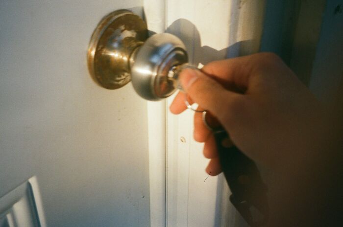 Hand turning a door k**b with a key, illustrating drunk fumbles and bad decisions in everyday moments.