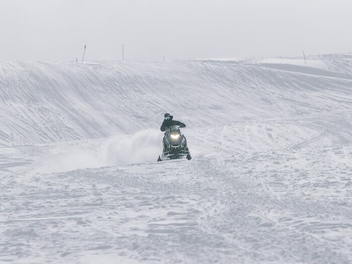 Person riding snowmobile on snowy terrain, illustrating moments the universe protected people from harm.