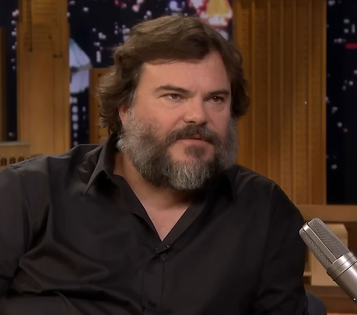 Actor with beard speaking into microphone during celebrity encounters interview on late night talk show.