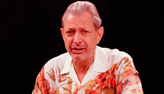 Man in a colorful floral shirt sharing personal encounters with celebrities against a black background.