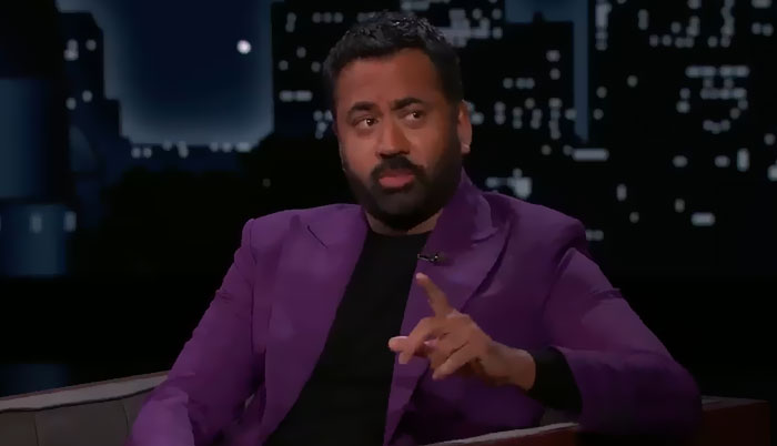 Comedian in a purple blazer sharing stories during a late-night talk show about encounters with celebrities.