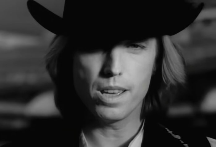 Close-up of a man in a black cowboy hat sharing a celebrity encounter in a black-and-white photo.