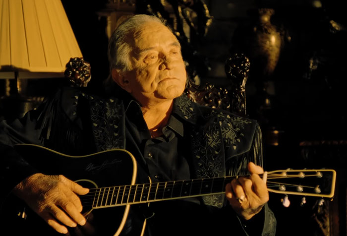 Older male celebrity playing guitar in a dimly lit room, highlighting memorable encounters with celebrities.