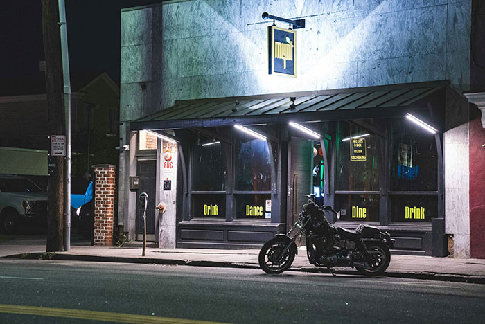 Motorcycle parked outside a dimly lit bar at night, capturing a mood of real and sobering life stories online.