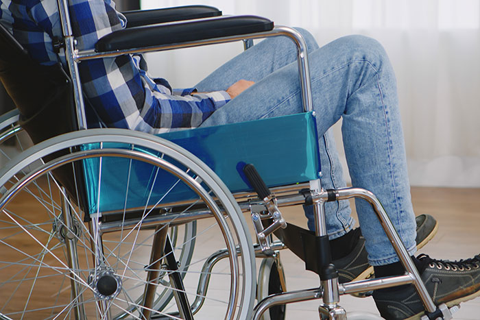 Person sitting in a wheelchair wearing jeans and a plaid shirt, illustrating how to ruin your entire life concept.