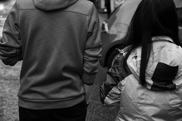 Two people seen from behind, wearing casual jackets, illustrating real and sobering stories about how to ruin your life.