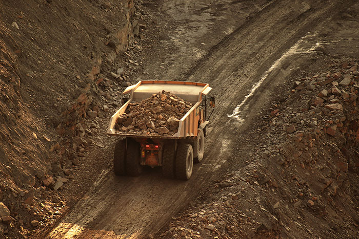 Large dump truck carrying rocks on a rugged dirt road in a mining site illustrating how to ruin your entire life.