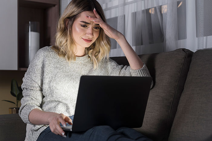 Young woman looking stressed while using a laptop at home, reflecting on real and sobering stories shared online.