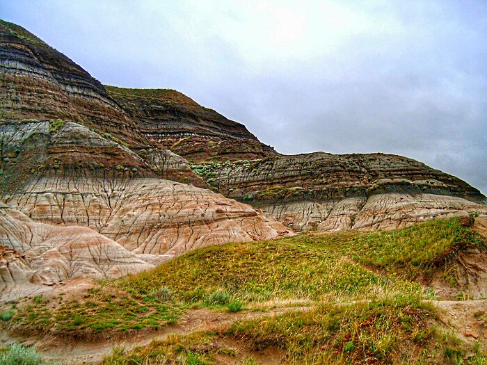 Layered rock formations and grassy hills under a cloudy sky, illustrating disturbing Wikipedia pages on dark rabbit holes online.