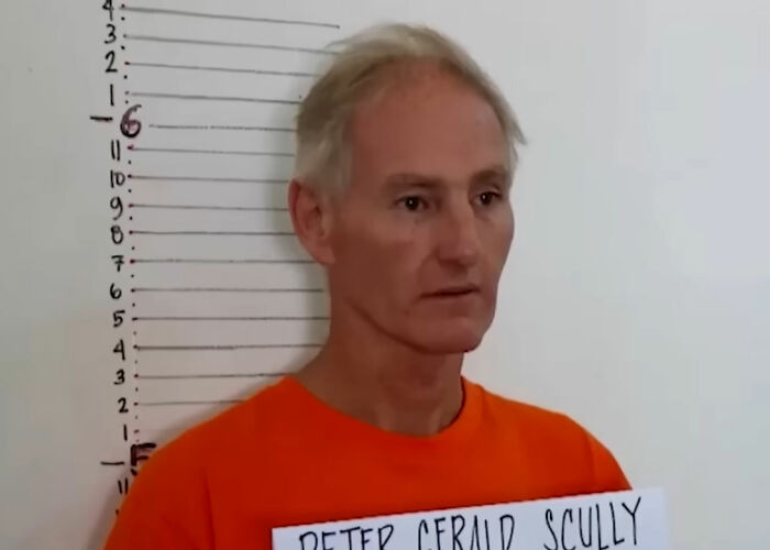 Mugshot of a man in an orange shirt against a height chart, illustrating disturbing Wikipedia pages and dark rabbit holes online.