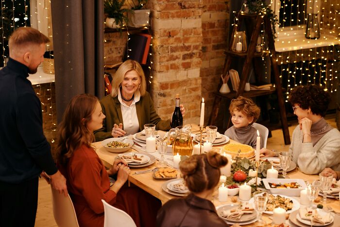 Family gathered around a festive dinner table sharing stories about childhood moments they still cringe about today.