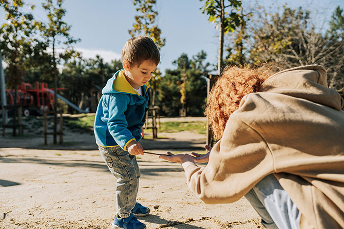 Young child and adult playing together outdoors, evoking true stories so creepy they’ll make you sleep with the lights on.