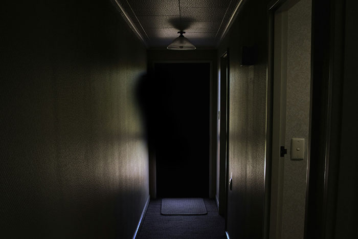 Dark, eerie hallway with a shadowy figure, illustrating creepy true stories to scare you this Halloween.