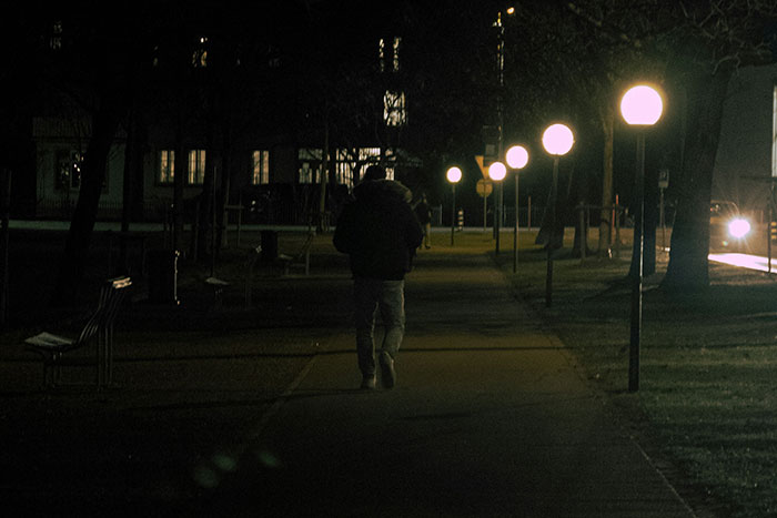 Person walking alone at night on a dimly lit path, evoking creepy true stories to make you sleep with lights on.
