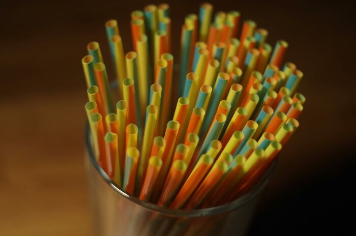Colorful plastic straws in a glass container, illustrating simple life hacks for everyday convenience and creativity.