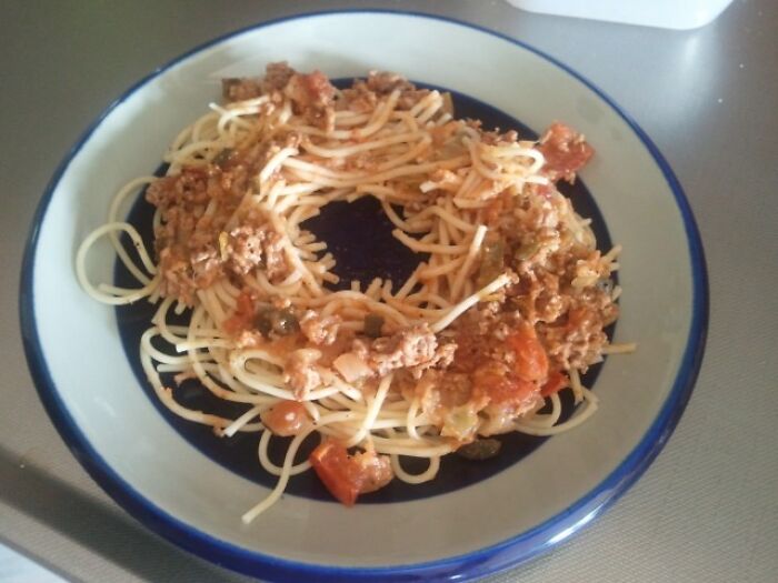 Spaghetti with meat sauce arranged creatively in a circular shape on a blue and white plate, showcasing unique life hacks.