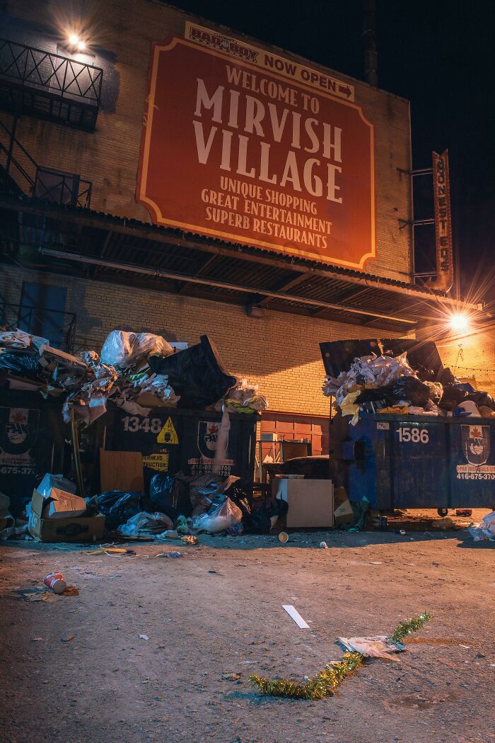 Overflowing dumpsters outside Mirvish Village at night, illustrating life hacks for waste and clutter management.