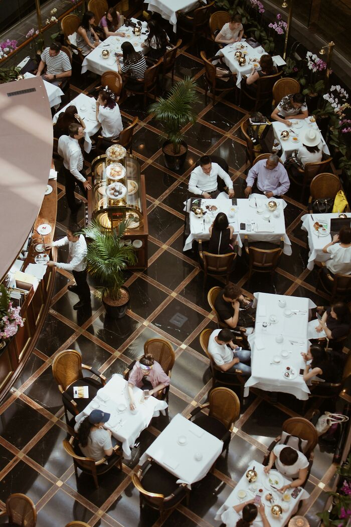 Overhead view of a busy restaurant with multiple tables and diners enjoying meals during a bustling service.