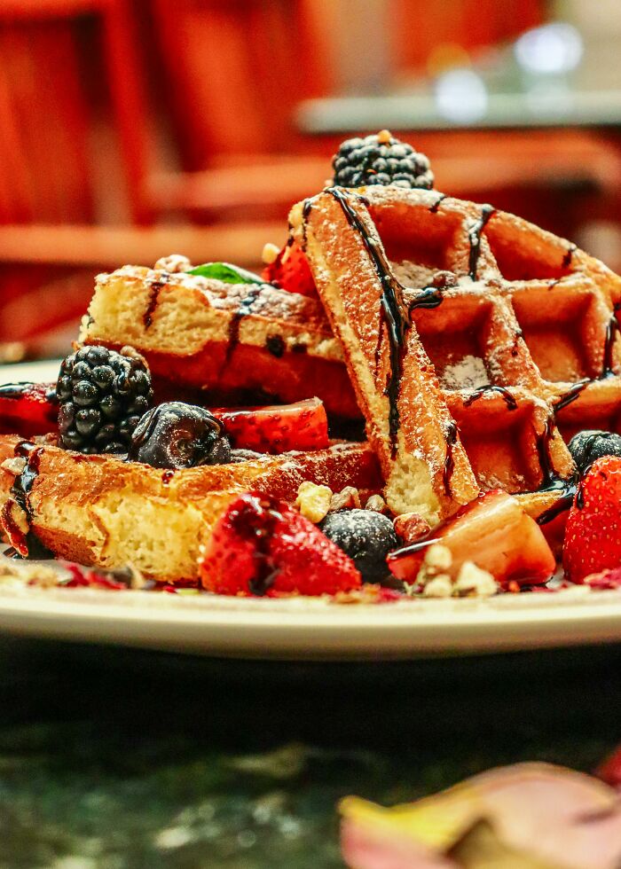 Waffles topped with fresh berries and chocolate drizzle, highlighting foods not popular in their country despite tourist expectations.