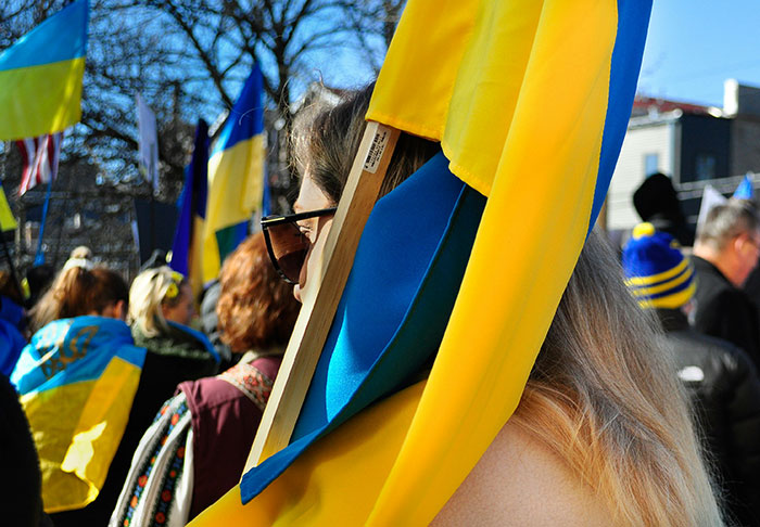Person holding Ukrainian flag at outdoor event, representing nightmare situations people survived against odds.