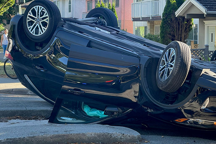 Black car flipped upside down on a residential street, representing nightmare situations people survived against the odds.