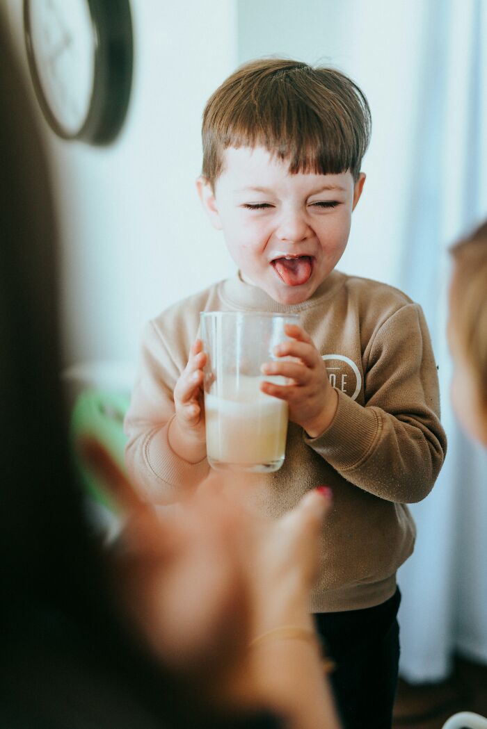 Child holding a glass of milk making a funny face, illustrating childhood rules that challenge therapists' expectations.