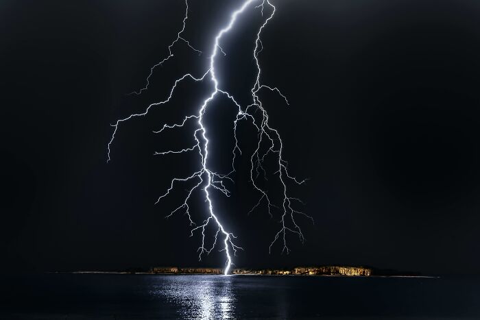Powerful lightning strike over a dark ocean reflecting on water, illustrating childhood rules impact on emotional storms.