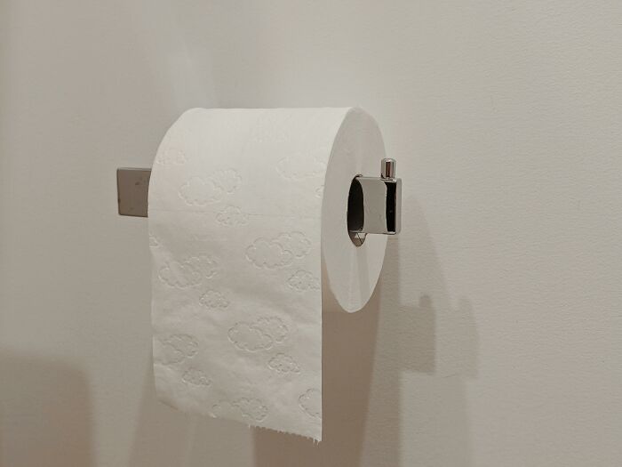 Roll of toilet paper with cloud patterns mounted on bathroom wall, reflecting simple childhood rules concept.