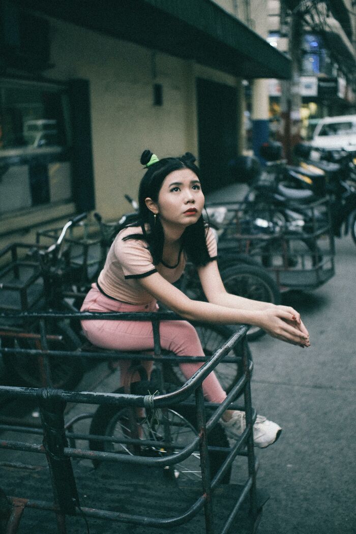 Young woman sitting thoughtfully in an urban setting, reflecting on childhood rules and emotional experiences.