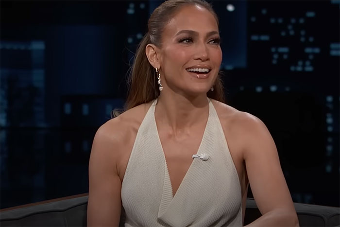 Celebrity encounter with a smiling woman in a white sleeveless top during a late-night TV interview session.