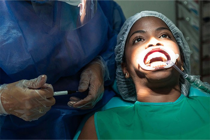 Patient with mouth open under dental surgery light, highlighting bone-chilling and hilarious stories of waking during surgery.