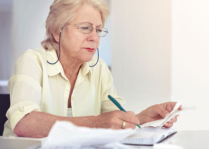 Elderly woman focused on writing, reflecting on real and sobering stories about how to ruin your entire life.