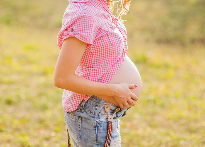 Pregnant woman holding her belly outdoors, illustrating one of the real and sobering stories about how to ruin your life.