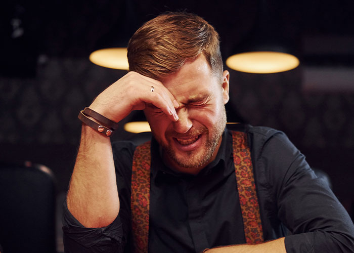 Man with hand on face, eyes closed, appearing distressed, illustrating the impact of how to ruin your life stories online.
