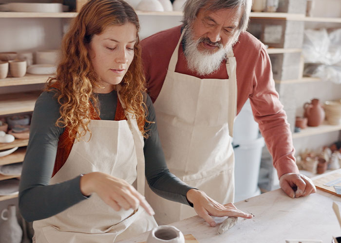 Woman and man in aprons crafting pottery together in a studio illustrating how to ruin your entire life stories.
