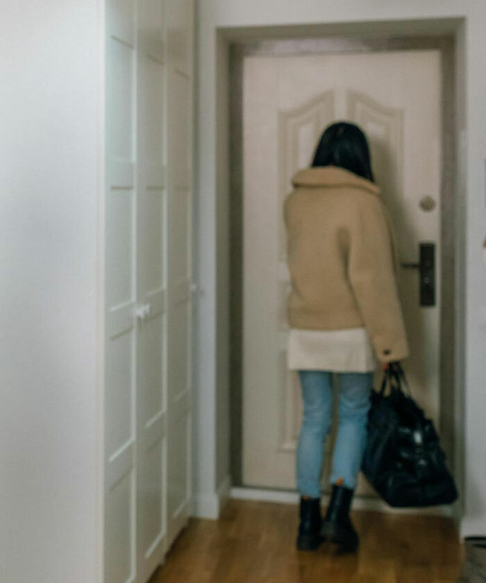 Woman standing by a closed door holding a bag, illustrating red flags and how spouses changed after the wedding.