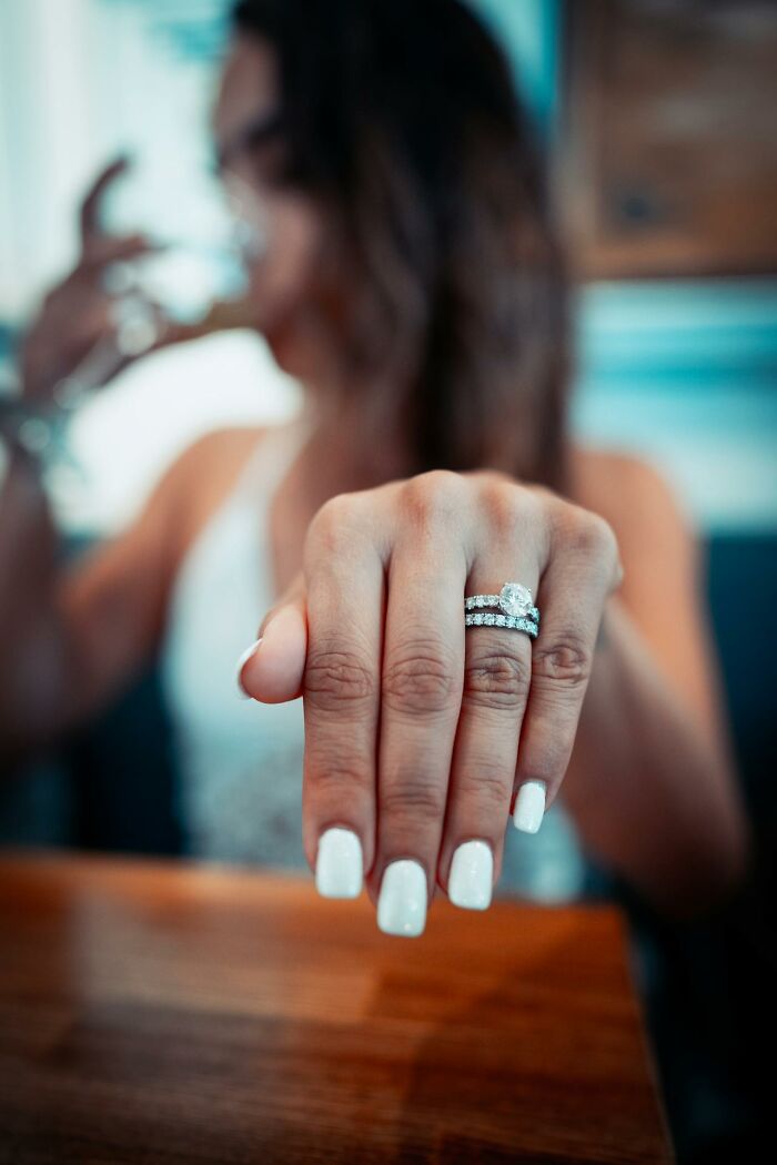 Woman showing engagement ring on hand with white nails, symbolizing secrets people are hiding from their partners.