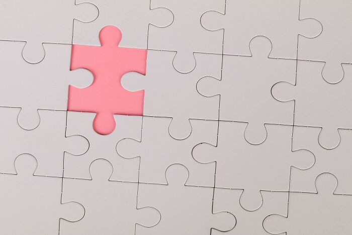 Partially completed white puzzle with one missing piece revealing a pink background, representing general knowledge puzzles.