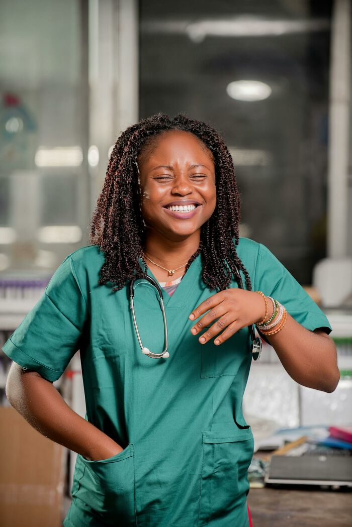 Smiling healthcare worker in green scrubs laughing, capturing moments of embarrassing and hilarious stories.
