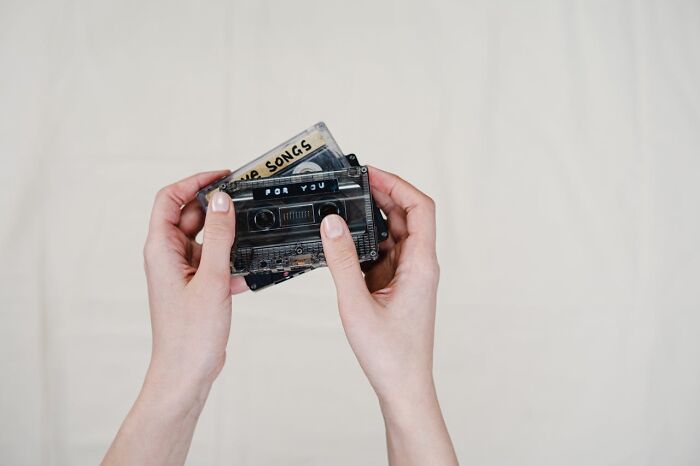 Hands holding vintage cassette tapes with handwritten labels, symbolizing chaotic breakup stories from exes.