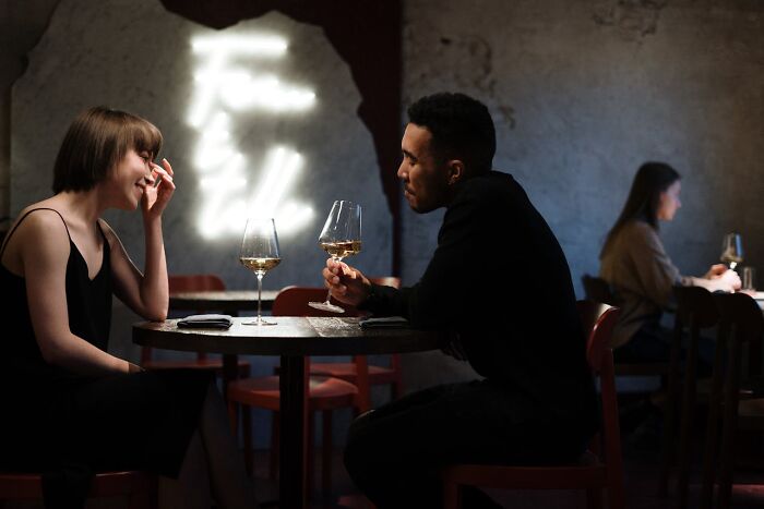 Couple sitting at a dimly lit table sharing wine, reflecting on disturbing things folks were told that seem creepy later.