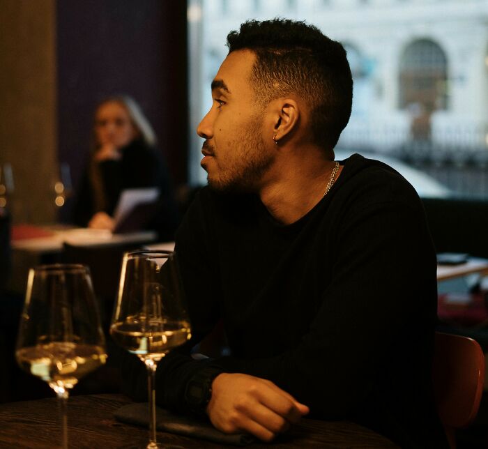 Man sitting alone at a restaurant table with two wine glasses, capturing a painful table for two moment turned table for one.