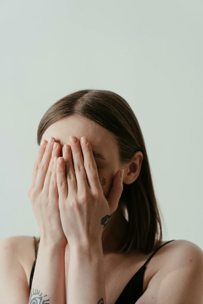 Young woman covering her face with hands, showing embarrassment, relating to people embarrassed moments and hilarious stories.