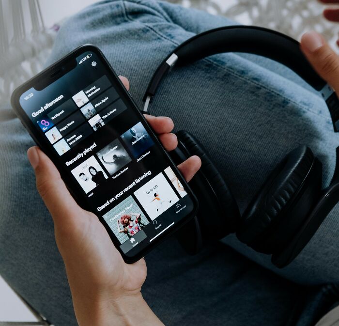 Person holding a smartphone with music app open, illustrating women sharing unhinged stalking stories for FBI skill proof.