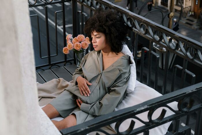 Pregnant woman sitting alone on a balcony, reflecting on chaotic and dramatic breakup stories involving unexpected parenthood.
