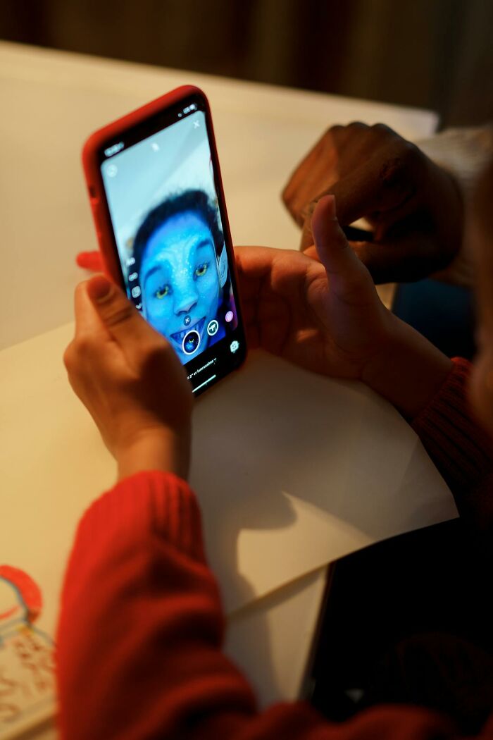 Person using phone with a blue face filter, illustrating online dating experience and digital interaction advice.