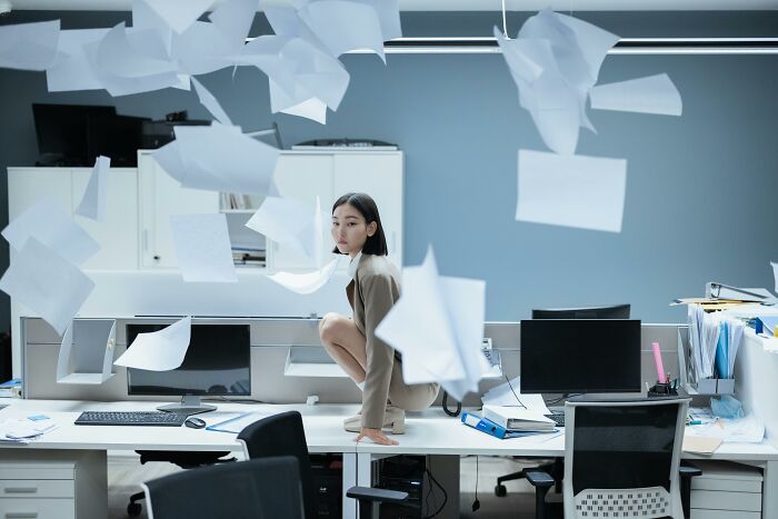 Young woman in office surrounded by flying papers, depicting drama queen or zen master emotions and reactions. Young woman in office surrounded by flying papers, depicting drama queen or zen master emotions and reactions.